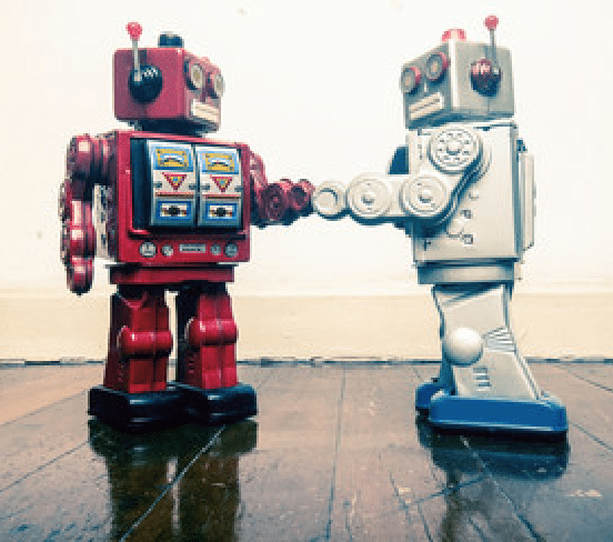 Red toy robot and white toy robot touching hands